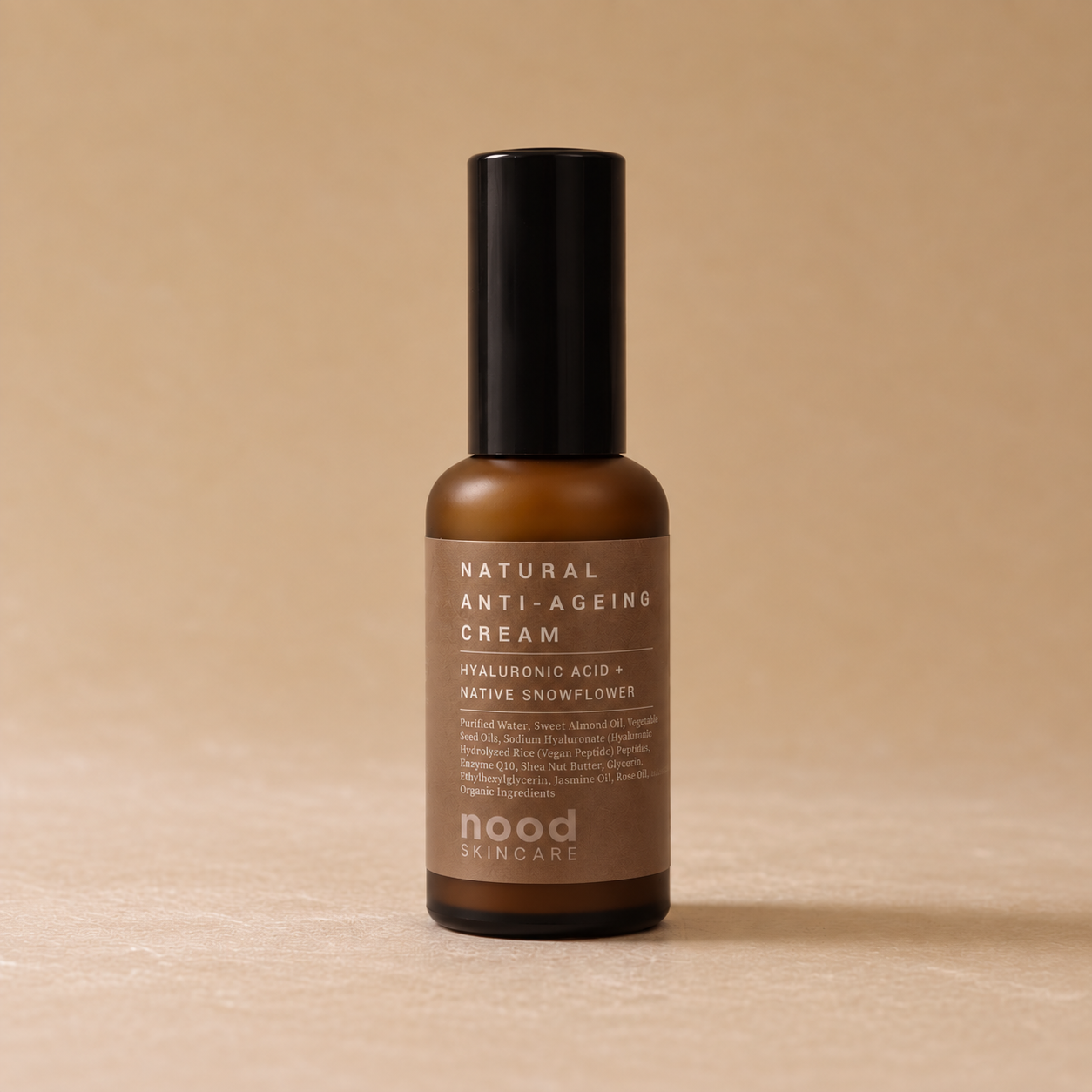 A bottle of Nood Skincare Natural Anti-Ageing Cream in an amber glass bottle with a black cap, set against a warm beige background.